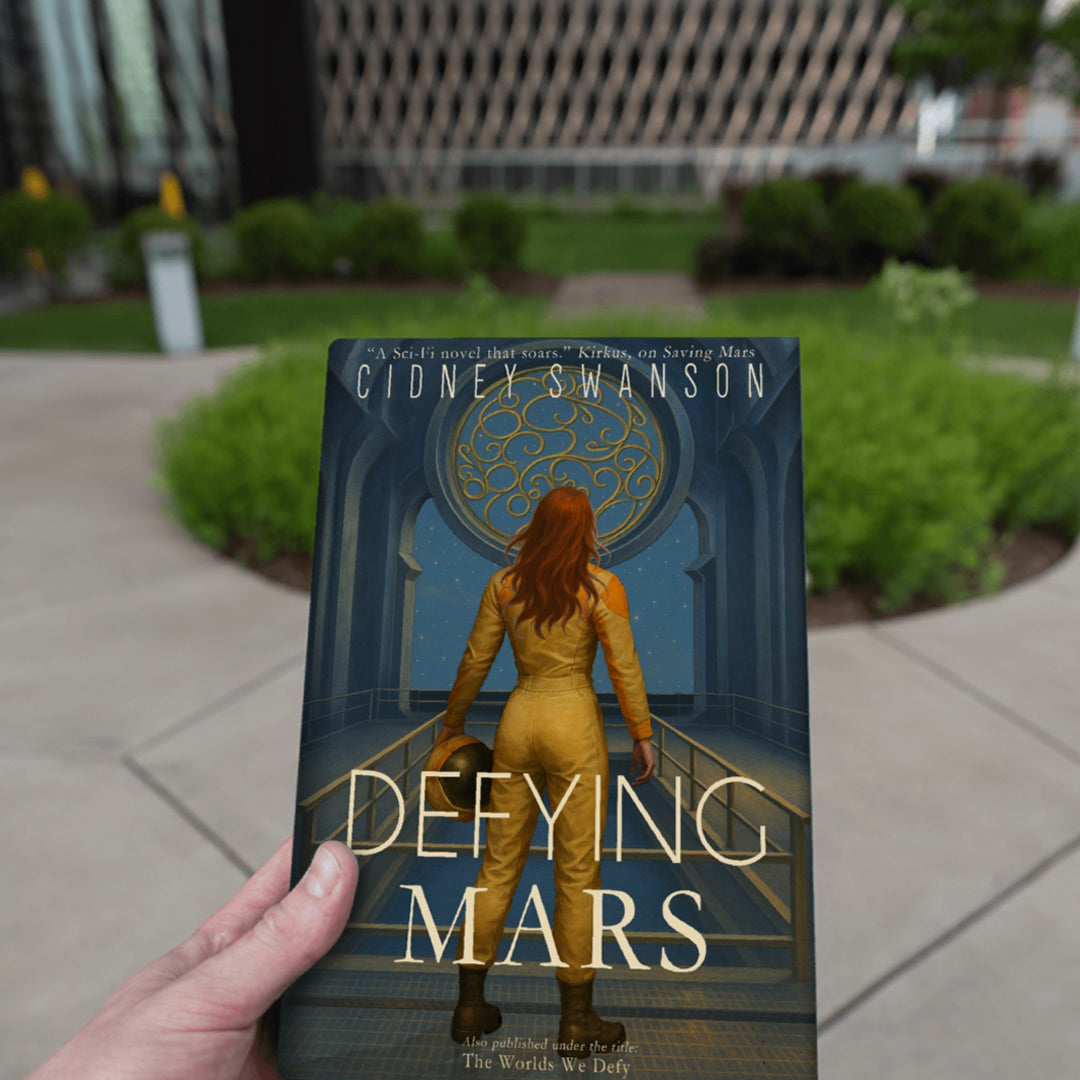 boy holding Defying Mars by Cidney Swanson — clean YA sci-fi for ages 10+, second in the Saving Mars series.