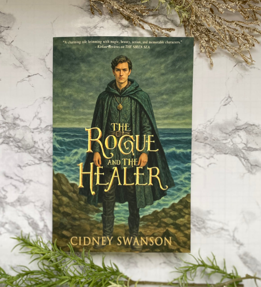 Paperback copy of The Rogue and the Healer by Cidney Swanson — clean YA fantasy for ages 12+, third in the Five Kingdoms Chronicles.