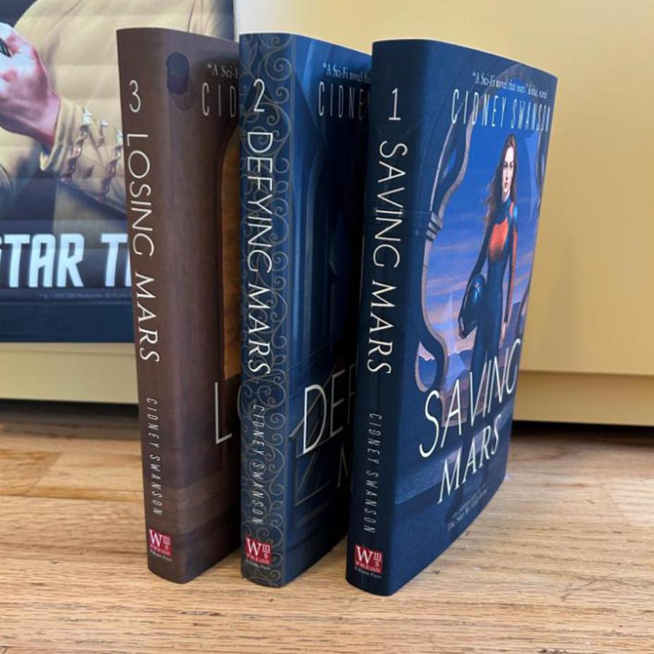 Saving Mars Hardcover bundle on wooden surface alongside memorabilia