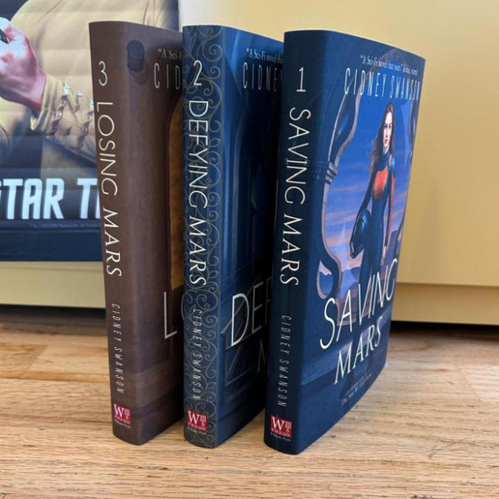 Saving Mars Hardcover bundle on wooden surface alongside memorabilia