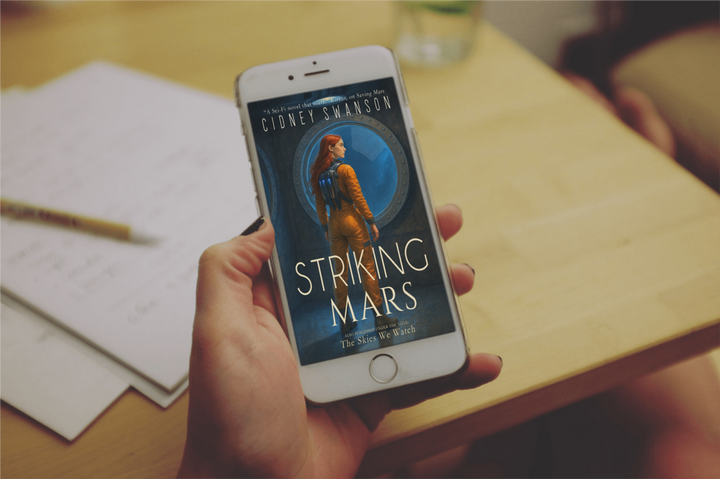 young woman holds Striking Mars by Cidney Swanson | clean YA sci-fi for ages 10+, part of the Saving Mars series.