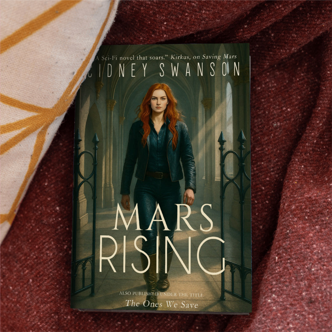 A copy of Mars Rising by Cidney Swanson — clean YA sci-fi for ages 10+, final book in the Saving Mars series, resting on a blanket.