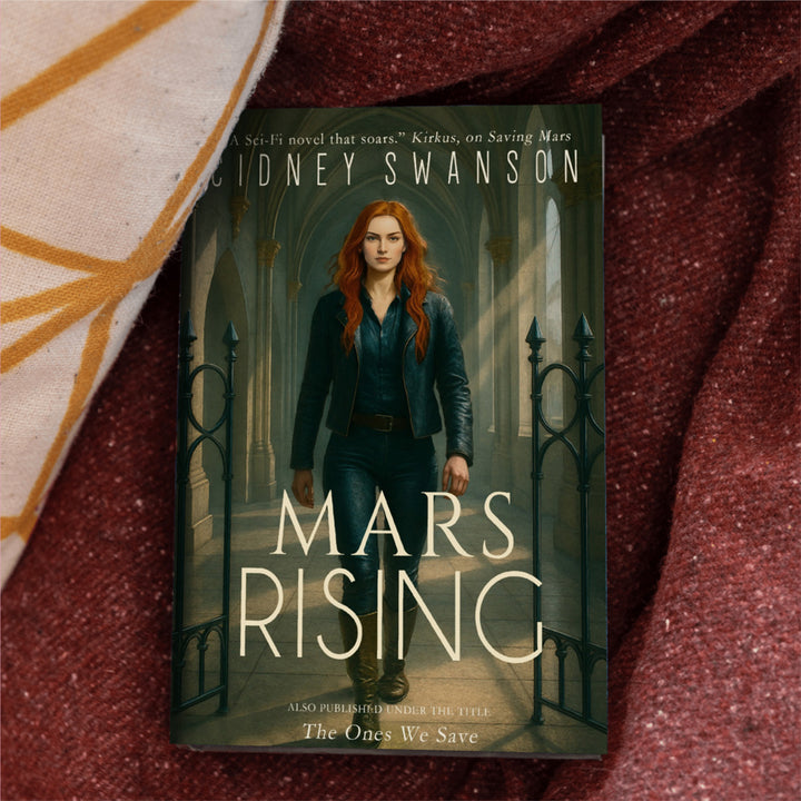 A copy of Mars Rising by Cidney Swanson — clean YA sci-fi for ages 10+, final book in the Saving Mars series, resting on a blanket.