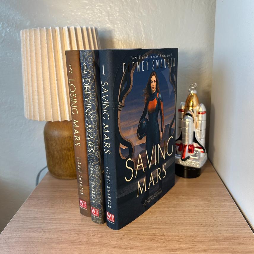 Saving Mars Hardcover bundle on wooden surface alongside memorabilia