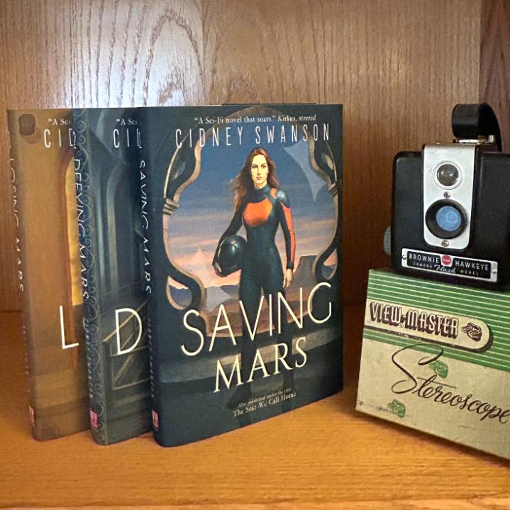 Saving Mars Hardcover bundle on wooden surface alongside memorabilia
