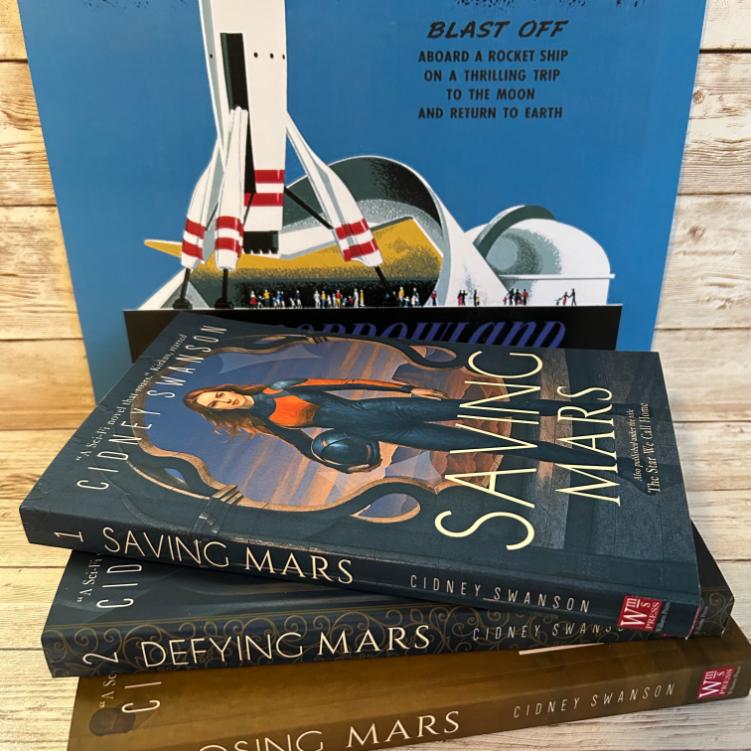 Saving Mars Hardcover bundle on wooden surface alongside memorabilia
