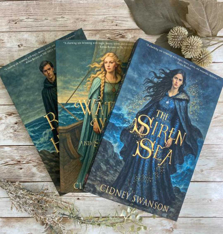 Four books by Cidney Swanson, covers shown on a wooden surface with decorative elements.