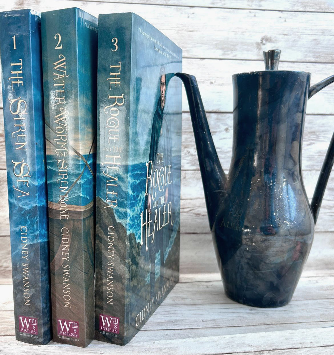 Siren Sea and two other books beside a teapot